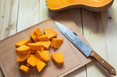 Ahşap kesme tahtası üzerinde ham turuncu kabak dilimlenmiş