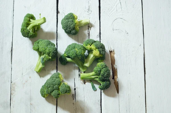 Verse rauwe biologische broccoli op houten witte achtergrond — Stockfoto