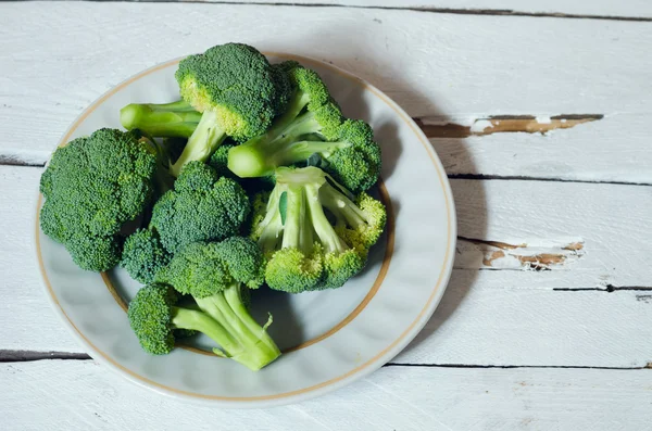 Verse rauwe biologische broccoli op houten witte achtergrond — Stockfoto