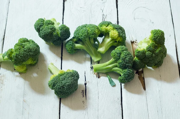 Ahşap beyaz zemin üzerine taze ham organik brokoli — Stok fotoğraf