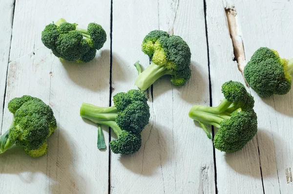 Broccoli freschi crudi biologici su fondo bianco in legno — Foto Stock