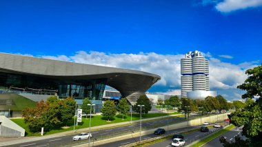 Münih, Almanya - 27 Eylül 2025. BMW Welt ve BMW Karargahı 4 silindir ve güneşli bir günde şehir yolu manzarası.