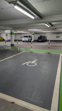 Uberlingen, Almanya - 14 Mart 2025. Yeraltı otoparkında engelli, engelli ve elektrikli araçlara ayrılmış park yerleri.