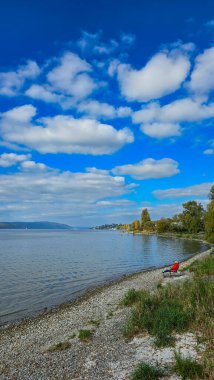 Güneşli bir sonbahar gününde Constance Gölü Sahili. Kadın sahilde bir kitap okuyor. Nussdorf, Almanya 'da Nell Kampı
