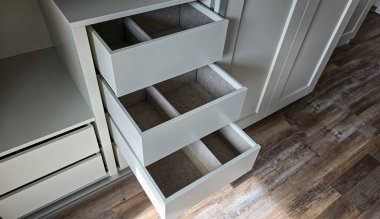 Beyaz bir gardıroba monte edilmiş gri organizatörlü açık çekmeceler. Sıralama ve düzenleme