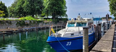 Uberlingen, Almanya - Haziran 08, 2024. Limandaki iskelede Baden-Wuerttemberg bayrağı taşıyan beyaz ve mavi bir polis gemisi..