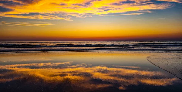 Renkli romantik bir günbatımı ya da Atlantik Okyanusu 'ndaki akış sırasında gün doğumu. Altın saat. Güneşin parlaklığı suya ve ıslak kuma yansıyor..