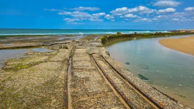 Atlantik kıyısının paslı demiryolu, İkinci Dünya Savaşı 'nın eski inşaatı. Arka planda Atlantik Okyanusu ve mavi bir gökyüzü var. Soulac-sur-Mer, Fransa.