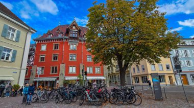 Uberlingen, Almanya - 01 Ekim 2025. Mansard çatısı, İtalyan dondurması kafesi ve renkli binaları olan büyüleyici kırmızı evin manzarası. Birçok bisiklet ön planda park edilmiştir..