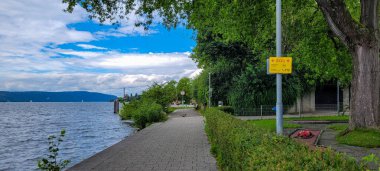 Uberlingen, Almanya - 30 Haziran 2024. Yeşil bitki örtüsü, çiçekler ve Avrupa 'da acil durum numarası 112 olan SOS mevcut konumu ile Constance Gölü dolumu.