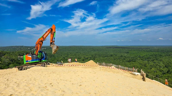 Pyla sur Mer, Fransa - 12 Haziran 2025. Kazıcı Hitachi 'nin çalışması Avrupa' nın en yüksek kum tepesinde, Pilat Kumulunda. Arka planda mavi bir gökyüzü ve yeşil çam ağaçları var..