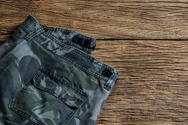 Camouflage pattern pants on wooden background — Stock Photo, Image