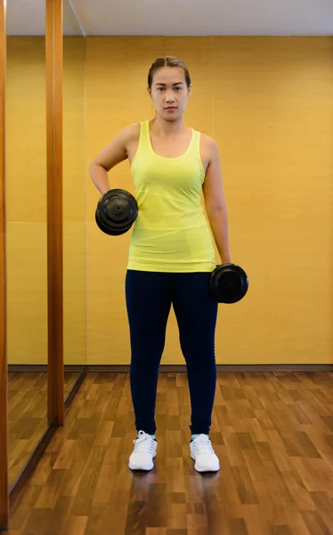 Mujer en un gimnasio haciendo Levante la mancuerna — Foto de Stock