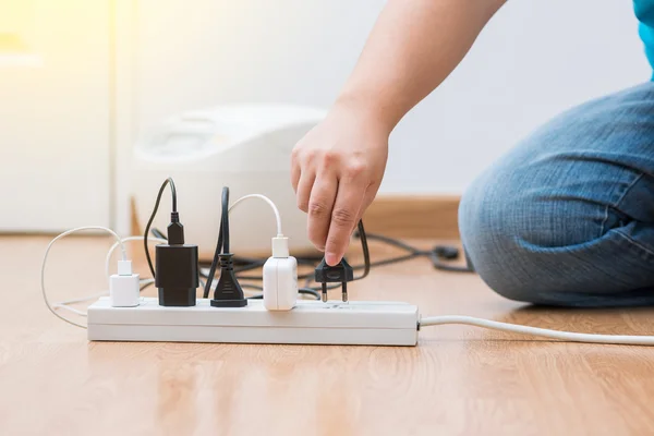 Mann zieht Stecker aus, um Energie zu sparen — Stockfoto