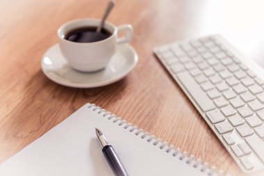 Ofis Masası not defteri, bilgisayar klavyesi ve kahve fincanı ve