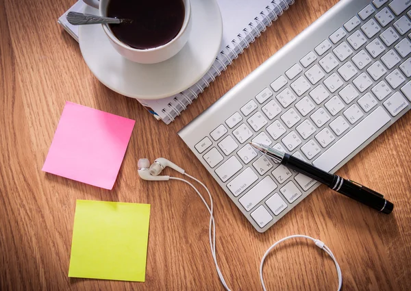 Not defteri, bilgisayar klavyesi, kahve fincanı, kalemile ofis masası ,