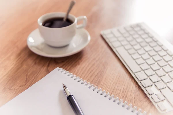 Tavolo da ufficio con blocco note, tastiera per computer e tazza da caffè e — Foto Stock