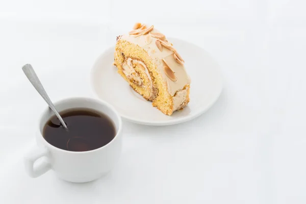 Almond roll cake on white dish with hot drink — Stock Photo, Image