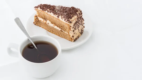 Rebanada de pastel de chocolate con rizo en plato blanco con bebida caliente — Foto de Stock