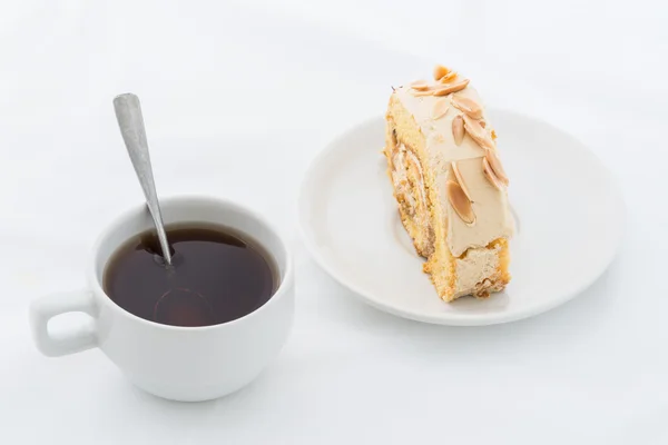 Almond roll cake on white dish with hot drink — Stock Photo, Image