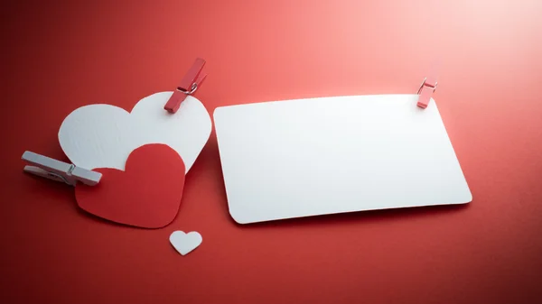 Corazones de papel de San Valentín con una tarjeta de visita en blanco y Clothesp —  Fotos de Stock