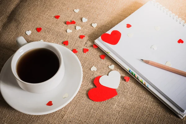 Šálek kávy a srdce na pytloviny textury — Stock fotografie