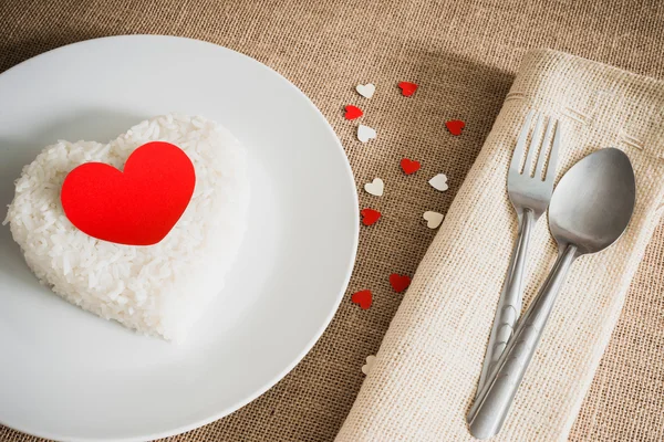 Červené srdce na rýži tvaru srdce na whiteplate — Stock fotografie