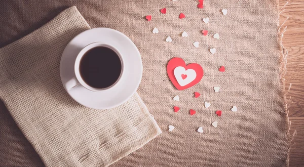 Šálek kávy a srdce na pytloviny textury — Stock fotografie