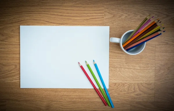 Lápices de color en taza de café blanco y papel blanco —  Fotos de Stock