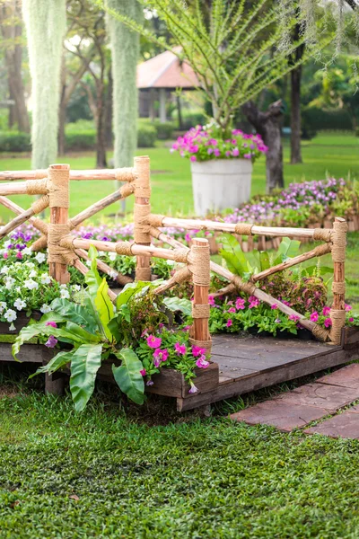Wooden pole, pathway and flower garden — Stock Photo, Image