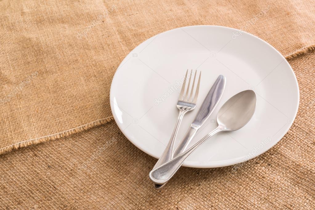 Empty white plate and  spoon, fork, knife