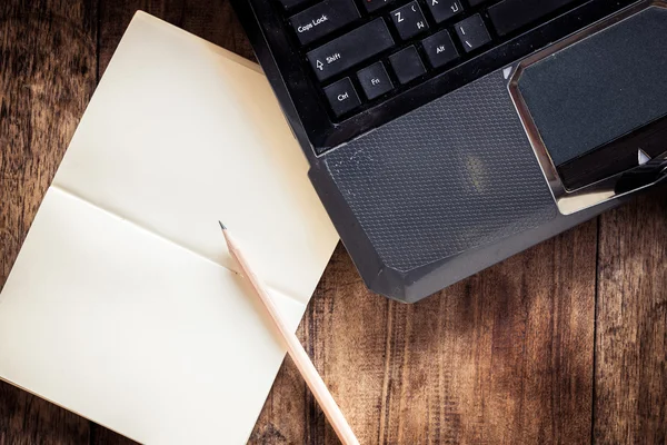 Leeres Notizbuch mit Bleistift auf Laptop — Stockfoto