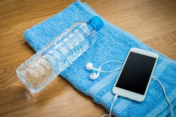 Botella de agua de plástico, auriculares, teléfono inteligente y toalla en el wo —  Fotos de Stock