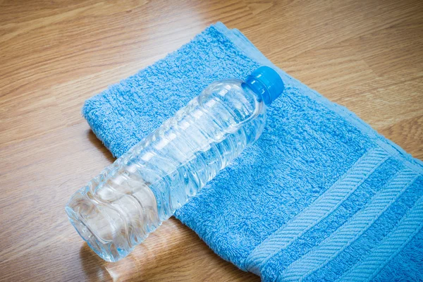 Botella de agua de plástico y toalla en la mesa de madera —  Fotos de Stock