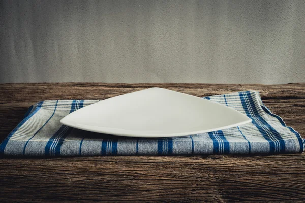 Prato branco em um guardanapo. em mesa de madeira — Fotografia de Stock