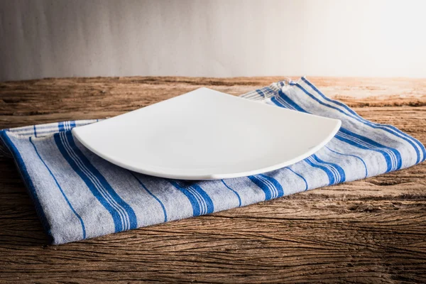 Placa blanca en una servilleta. sobre mesa de madera — Foto de Stock