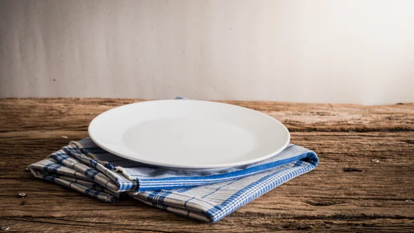 Prato branco em um guardanapo. em mesa de madeira — Fotografia de Stock