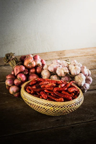 Uien, knoflook en droge chili op houten tafel — Stockfoto