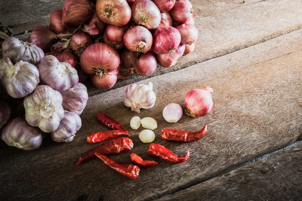 Cibuli, česnek a suché chilli na dřevěný stůl — Stock fotografie