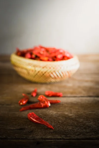 Gedroogde chilipepertjes in bamboe mand op houten tafel — Stockfoto