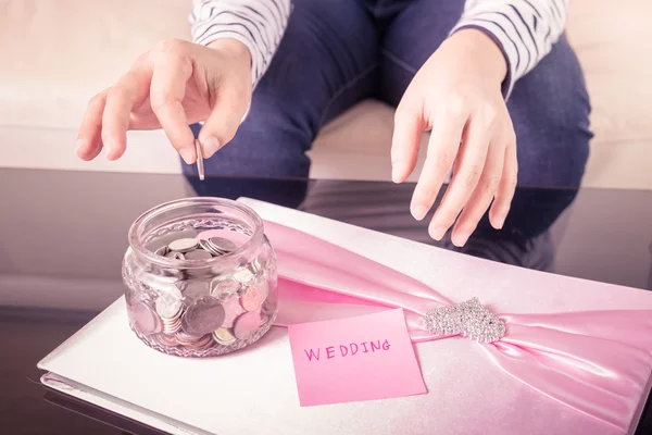 Hand steckt eine Münze in Glasgefäße mit "Hochzeitstext" — Stockfoto