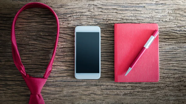 Corbata roja, bolígrafo, cuaderno, smartphone en mesa de madera — Foto de Stock