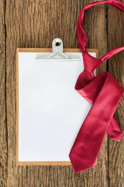 Old clipboard, red necktie on grungy wooden surface — Stock Photo, Image