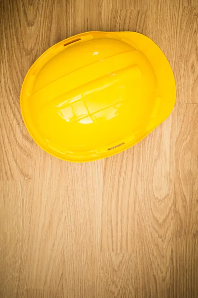 Capacete de proteção industrial amarelo no fundo de madeira — Fotografia de Stock