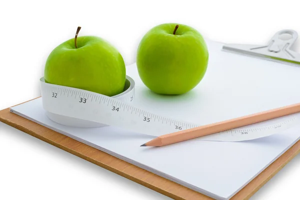 Measuring tape wrapped around a green apple and clipboard Stock Photo