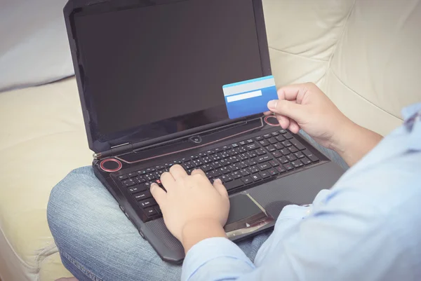 Close up de homem com computador portátil e cartão de crédito em casa — Fotografia de Stock