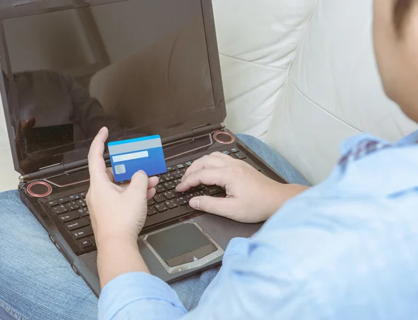 Primer plano del hombre con ordenador portátil y tarjeta de crédito en casa —  Fotos de Stock