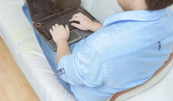 Close up of man working with laptop computer and sitting on sofa — Stock Photo, Image