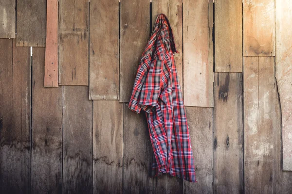 A velha camisa xadrez enrugada pendurada no fundo de madeira — Fotografia de Stock