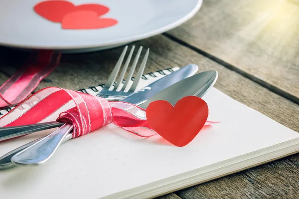 Valentinky den stůl s deskou, nůž, vidličku, červenou stužku — Stock fotografie
